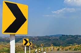 Chevron traffic signs line the side of a road with a horizontal curve.