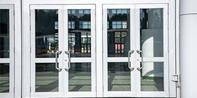 Exterior photo of building entrance with two sets of glass double doors
