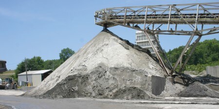 A large pile of finely ground Nepheline Syenite coming from an industrial conveyor belt
