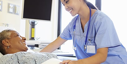 A patient and nurse smile in a hospital room with natural light coming through the windows using 3M sun blocking window film.
