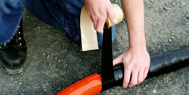 worker wrapping cable in protective electrical tape
