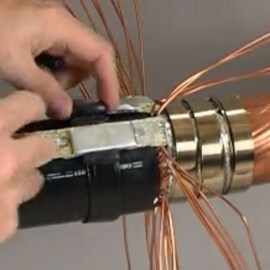Photo with video play button superimposed of hands pulling copper wires back on a 3M Cold Shrink QS-III Joint