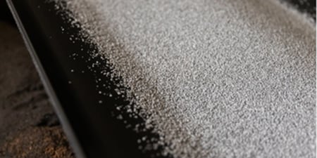 White ceramic coated mineral roofing granules used in residential and commercial roof coverings on a conveyor belt
