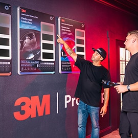 A technician points to 3M product boards in a Pro Shop display area, highlighting dealer‑only product access.
