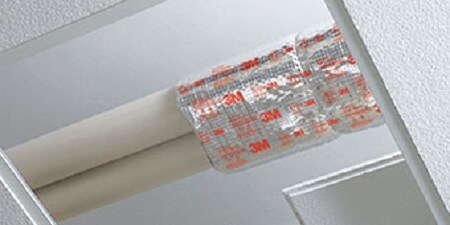 Two pipes covered halfway by a fire protective wrap.
