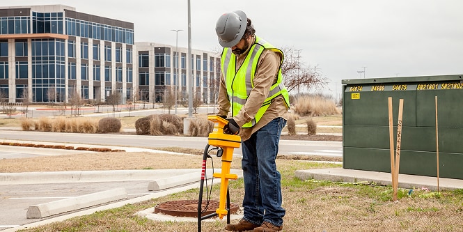 Worker outside in safety gear using yellow locator
