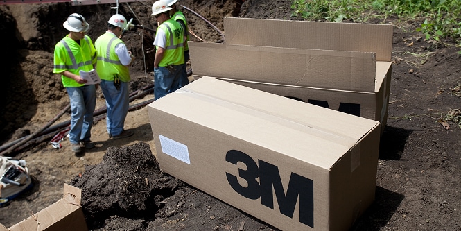 Worker outside in safety gear using yellow locator

