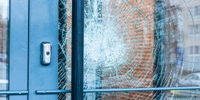 Close up photo of glass door with large cracked impact
