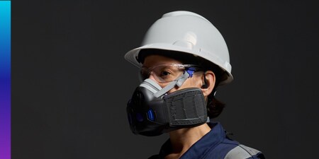 Person wearing a white safety helmet and a 3M Seguro click respirator against a dark background.
