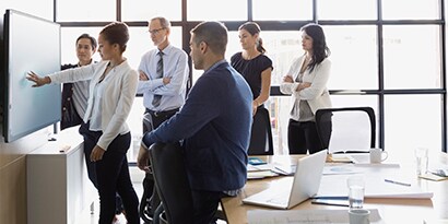 Group of businesswomen and businessmen at interactive touch display
