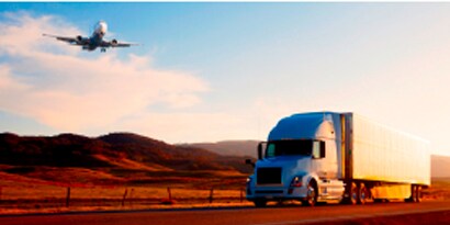 commercial truck on a highway with an airplane flying overhead.
