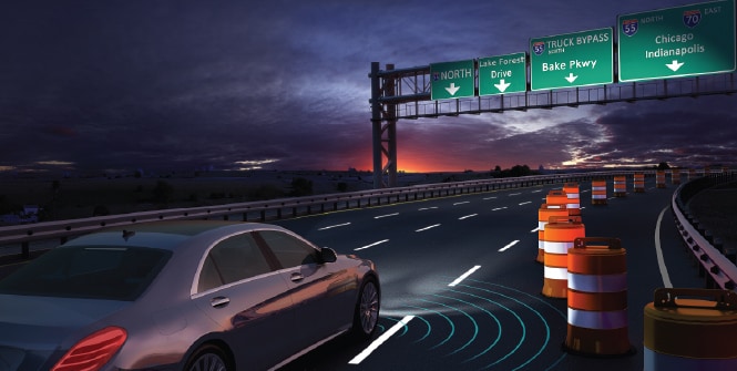 Car on a highway passing reflective traffic cones and overhead signage.
