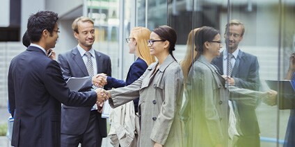 Photo of business people shaking hands outside windows with mirror finish
