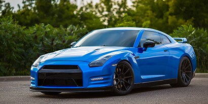 A sports car’s vehicle wrap is electric blue and reflects its surroundings.

