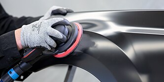 collision tech using sander on car panel for blending and denibbing
