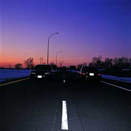 License plates on two vehicles clearly visible at dusk due, showing the benefit of cutting-edge reflective license plate sheeting.