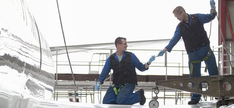 Aircraft maintenance technicians working on an airplane surface.
