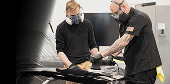 two workers in protective equipment using a buffer.