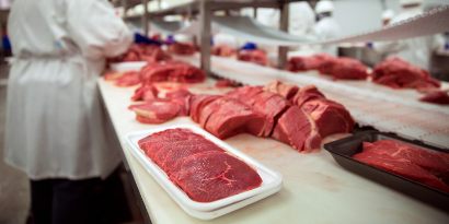 A worker packaging meat at a meat processing facility.
