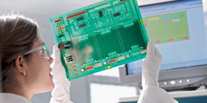 Female scientist inspecting circuit board
