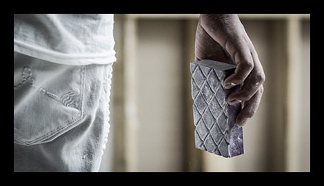 Contractor holding a 3M Pro Grade Precision purple sanding sponge with textured diamond grip surface.