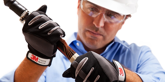 Worker in safety gear inspecting electrical cable
