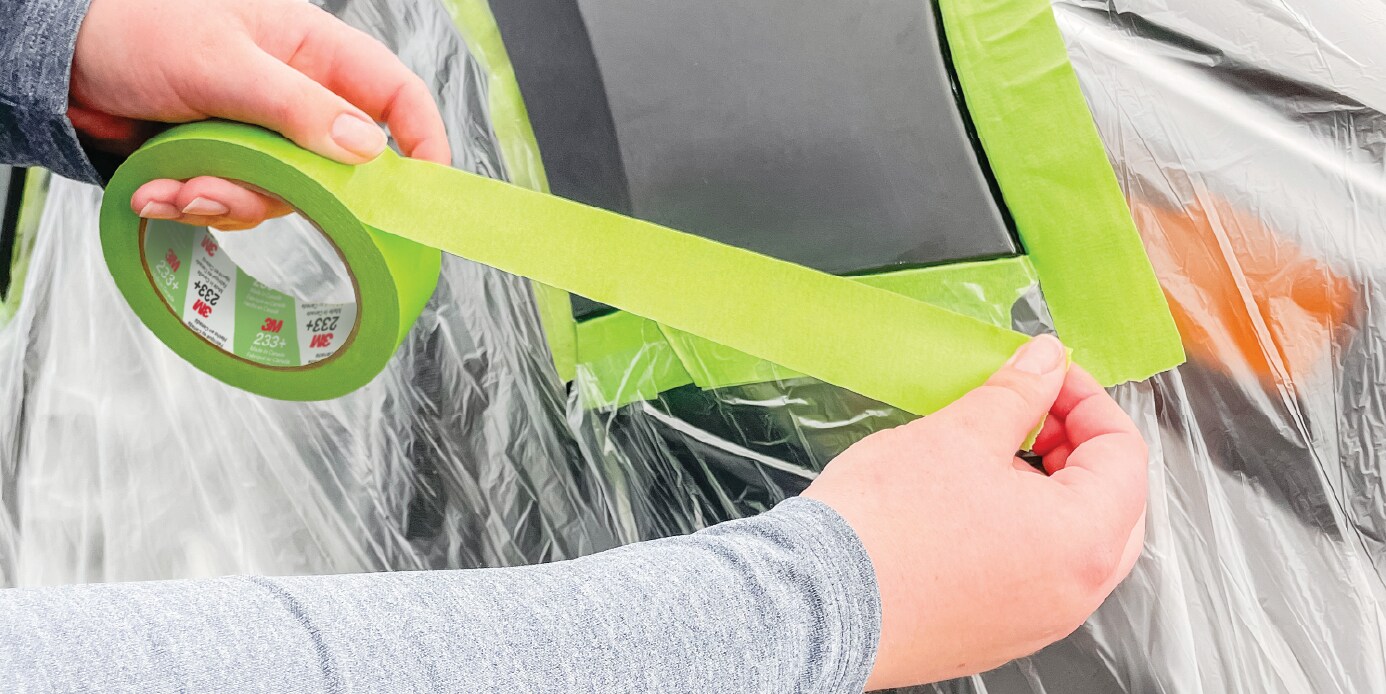 body technician taping off a section of a vehicle