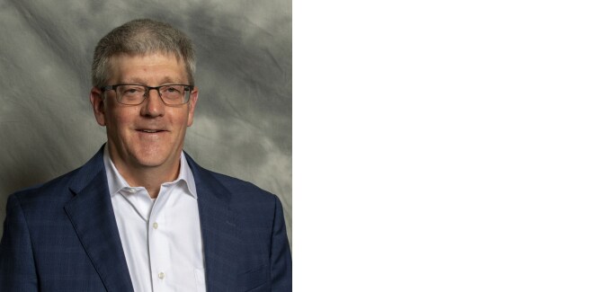 Portrait of David Hays against gray textured cloth background.
