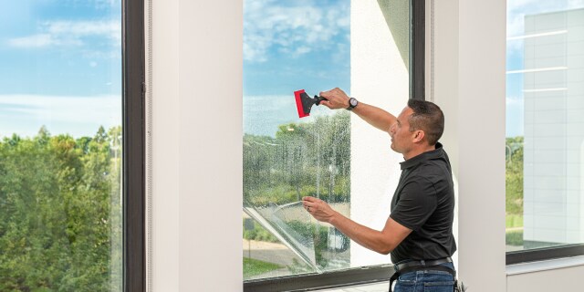Person applying window film with a squeegee.
