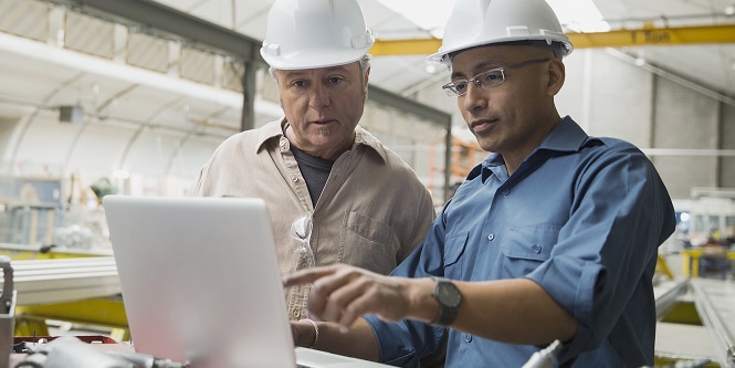 Two men discussing something in front of laptop
