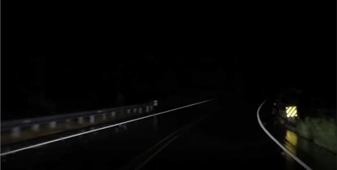 Dark night road with retroreflective sign.
