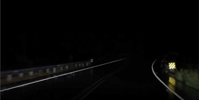 Dark night road with retroreflective sign.
