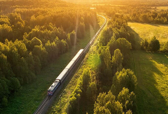 Train moving through a forest, representing improved cooling and rail performance.
