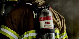 Firefighter wearing 3M Scott breathing apparatus during active emergency response.
