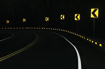 Curve on road at night with bright pavement markings and signs.
