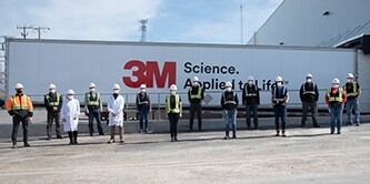 3M lab and transportation teams standing outside of a 3M branded truck.
