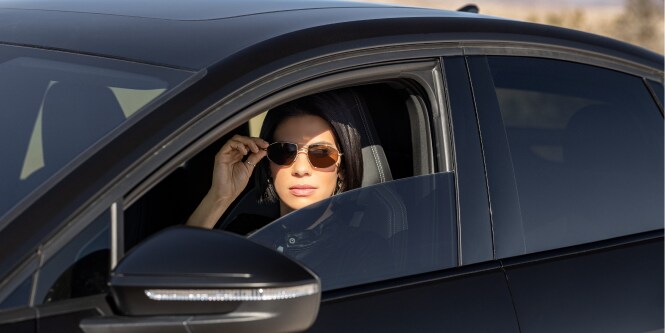 women in car with tinted rolled down window

