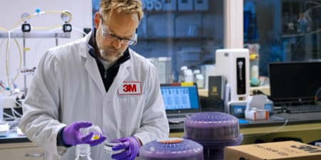 3M researcher in a white 3M lab coat doing an experiment.
