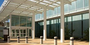 Exterior photo of building entrance with large atrium and windows
