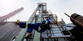 Industrial worker welding metal with protective gear and sparks flying.
