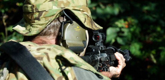 Solider wearing a tactical communications headset that includes hearing protection.

