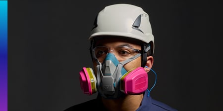 Person wearing a white safety helmet, P-100 dual‑cartridge respirator, and blue corded 3M earplugs.

