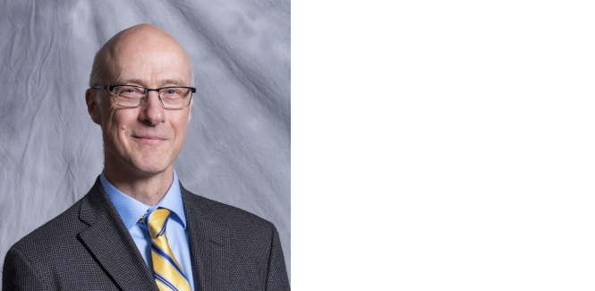 Portrait of Matthew Atkinson against gray textured cloth background.

