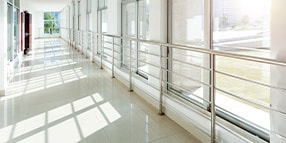 Interior photo of while hallway with windows and sunlight shining in
