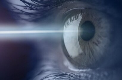 A beam of light travels to an eye that fills the frame, illustrating elderly drivers’ need for bright signs.