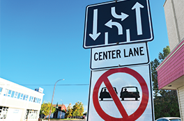 Road signs with diagram of three-lane road, words CENTER LANE and warning for vehicles not to drive side-by-side. 
