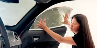 woman installing window tint on the inside of a passenger car window
