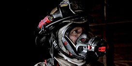 firefighters walking through a smokey building
