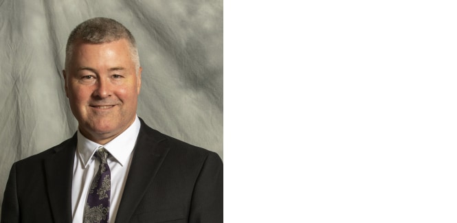 Portrait of Eric Nelson against gray textured cloth background
