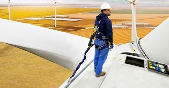 Worker standing on a wind turbine wearing a self-retracting device.
